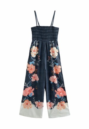 Donkerblauwe mouwloze jumpsuit met wijde pijpen, geplooide lijfje en grote perzik- en lichtblauwe bloemenpatronen langs de pijpen, witte zoomdetails.