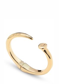 Brazalete de metal dorado con superficie lisa y pulida, diseño sutilmente torcido y cierre redondeado.