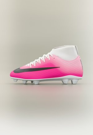 Chaussure de football blanche et rose avec un logo Nike noir, des lacets et des crampons moulés, vue de profil sur fond beige.