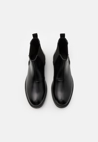 Botas Chelsea de cuero negro con paneles laterales elásticos, tiradores y un acabado suave. Incluyen una suela de goma y un diseño discreto.