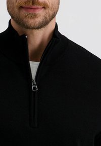 Schwarzer Zip-Up-Pullover mit hohem Kragen, aus weichem Material gefertigt. Verfügt über einen silbernen Reißverschluss und gerippte Akzente am Kragen und Saum.