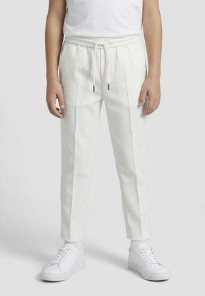 Enfant portant un pantalon slim blanc avec des plis sur le devant, taille élastique avec cordon, assorti à des chaussettes blanches et des baskets.