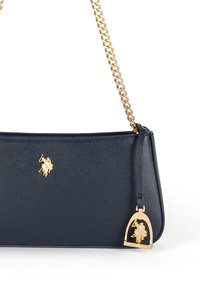 Marinblå läderhandväska med ett guld kedjestrap och en liten guldberlock. Väskan har en guld polo-spelare logo på framsidan.