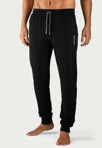 Zwarte joggingbroek van zachte stof met een elastische tailleband, verstelbaar trekkoord en boorden. Heeft een subtiele merkl logo aan de zijkant.