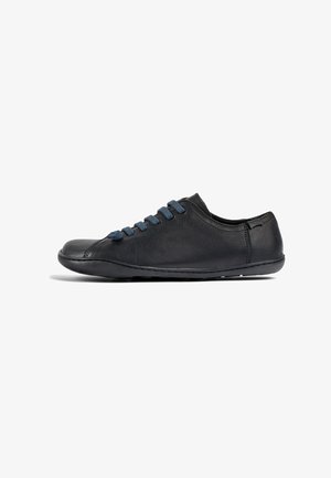 Sneaker in pelle nera con punta arrotondata, dotato di lacci in suede blu, profilo basso e dettagli di cucitura minimi sui lati.