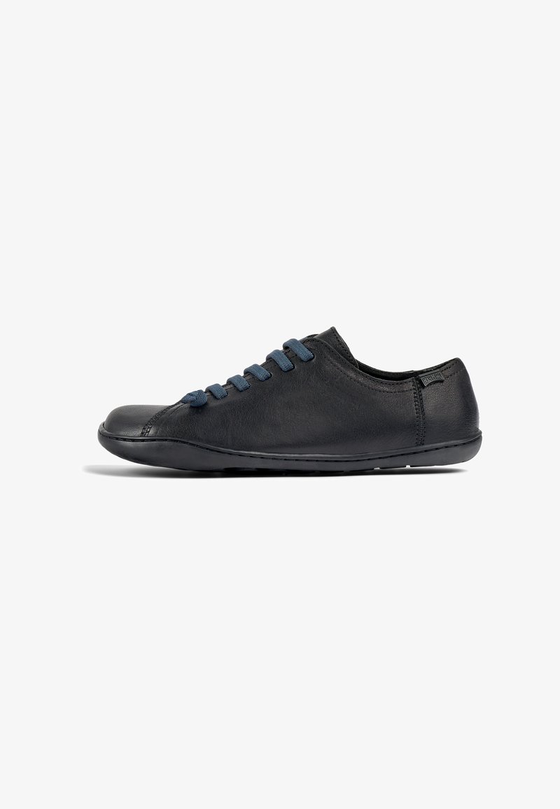 Black leather sneaker with a rounded toe, featuring blue suede laces, a low profile, and minimal stitching details on the sides.