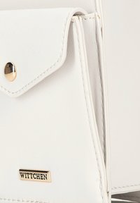 Borsa in pelle bianca con chiusura a pattina, dettagli in metallo dorato e cuciture visibili. Presenta il logo del marchio "WITTCHEN" sul fronte.