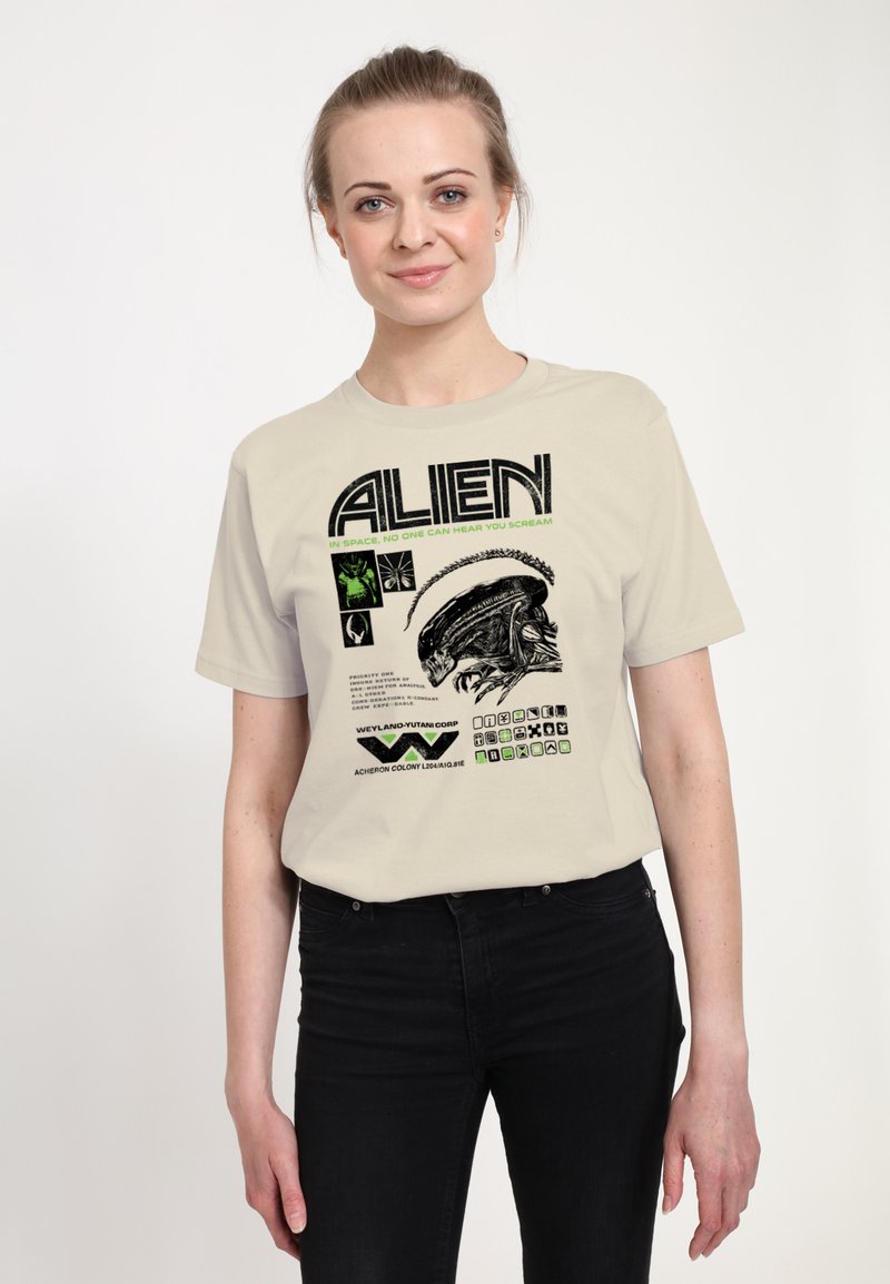 Kremowy bawełniany T-shirt z czarno-zielonym nadrukiem graficznym przedstawiającym głowę obcego oraz napisami z filmu "Obcy". Dopasowany fason z krótkimi rękawami.
