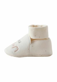 Soft cream-colored baby bootie with folded cuff and subtle embroidered design on the toe, shown from the side on a white background.
