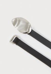 Zwarte leren riem met een glanzende zilveren metalen gesp, ovale vorm, voorzien van een subtiele logo-engraving en een gladde textuur.