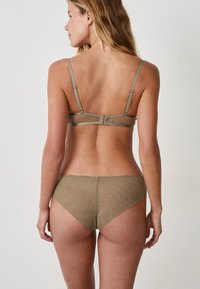 Set di lingerie verde oliva composto da un reggiseno in rete con spalline regolabili e chiusura a gancio, abbinato a bikini trasparenti coordinati.