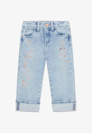 Jean en denim bleu clair avec revers roulés, fleurs roses et cœurs brodés, et un petit logo "Guess" sur la cuisse droite.