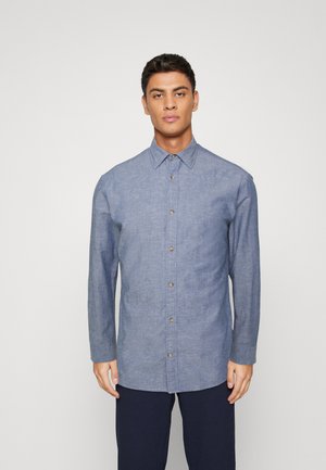 Camicia in chambray blu con colletto a punta, maniche lunghe e chiusura anteriore con bottoni. Il tessuto è leggero con una finitura strutturata.