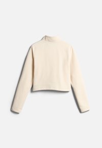 Top corto de manga larga en suave tela color crema con cuello tipo chimenea, que presenta una textura lisa y un diseño minimalista. Sin patrones visibles.