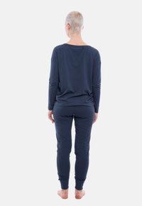 Navy blue loungewear set made of soft fabric; long-sleeve top with loose fit and matching fitted pants with cuffs at the ankles.