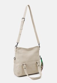 Beige strukturierte Tragetasche mit verstellbarem Riemen, ausgestattet mit zwei seitlichen Griffen und dekorativen mehrfarbigen Quasten.