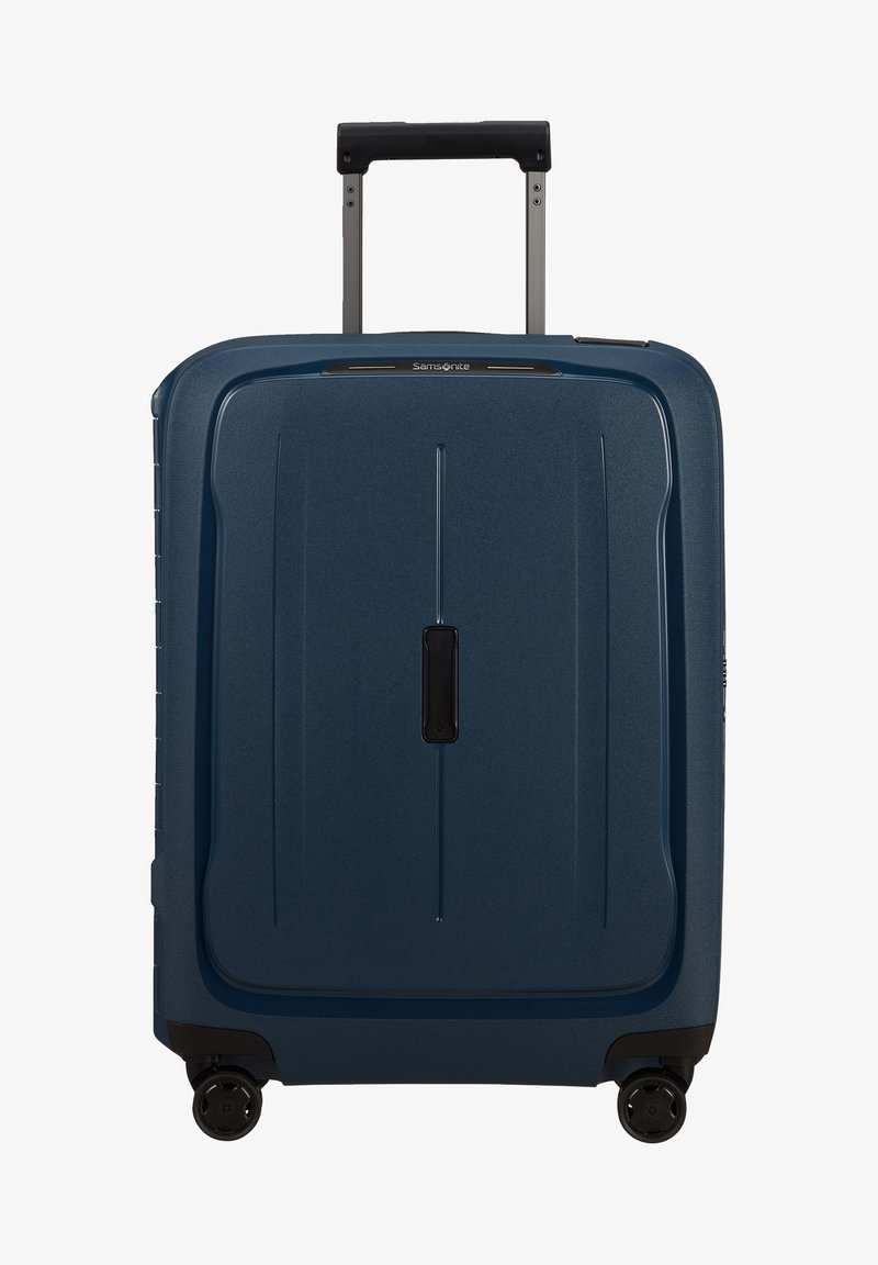 Valise rigide de couleur bleu foncé, avec une surface texturée, une poignée rétractable et quatre roues pivotantes noires. Design minimaliste avec des lignes verticales.