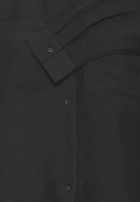 Black shirt with two chest pockets, button closure, and long sleeves. The fabric has a slightly textured finish. Buttons are black.