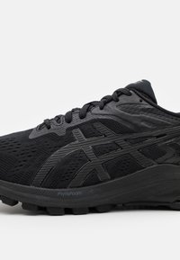 Svart löparsko med texturerad mesh-övre, snörning, vadderad FlyteFoam-sula och en blank sidologotyp på vit bakgrund.