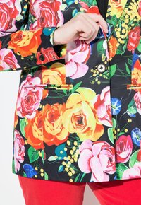 Blazer med blommönster på svart bakgrund, prydd med livliga rosor i rosa, gult och rött. Inkluderar två framfickor och en knappdetalj.
