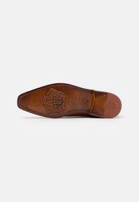 Semelle de chaussure en cuir de couleur marron, de forme pointue. Présente un logo en relief et des motifs décoratifs, avec une texture lisse et polie.