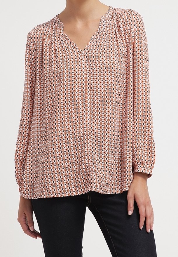 Blusa a manica lunga con stampa geometrica in sfumature di arancione e bianco. Presenta un collo a V e dettagli arricciati lungo le spalle.
