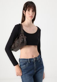 Black long-sleeve crop top paired with blue denim jeans and a brown leather handbag featuring gold hardware and a rounded shape.