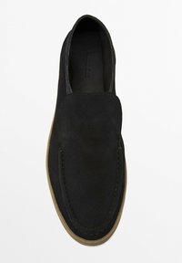 Černá semišová obuv na slip-on s zaoblenou špičkou, kontrastní hnědou gumovou podrážkou a švy podél horního okraje.