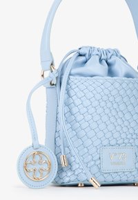 Sac à main en cuir tressé bleu clair avec une fermeture à cordon, une poignée arrondie, un pendentif en métal doré et une étiquette de marque. Détails de texture lisse évidents.