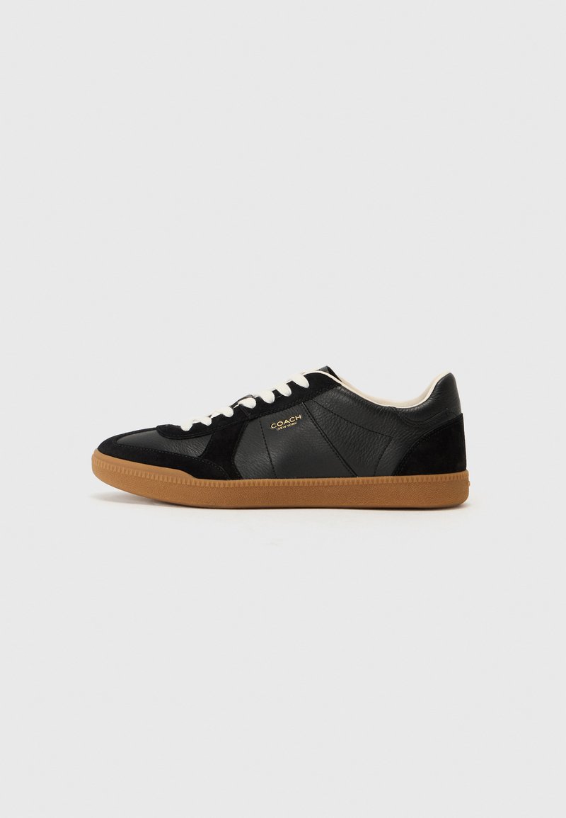 Black leather and suede sneaker with a gum outsole, white laces, and embossed logo detail on the side. Features a low-profile design.
