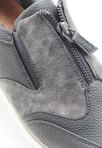 Zapato de cuero gris con acabado texturizado, cremallera lateral y panel elástico. Forma redondeada con suela blanca y detalles de costura sutiles.