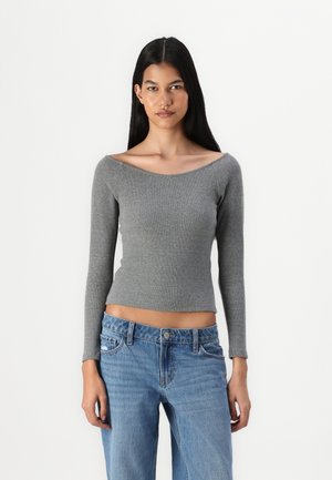 Gray ribbed long-sleeve top with an off-the-shoulder neckline, paired with light blue jeans featuring a classic five-pocket design.