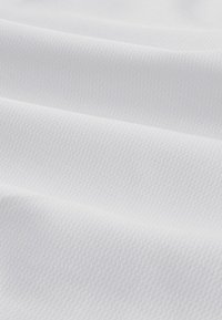 Biely textúrovaný látka s jemným zvislým vzorom, ktorý obsahuje hladké, vlnené záhyby, vytvárajúce hĺbku a dimenziu.