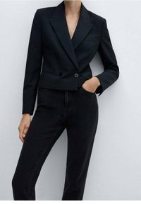 Černé upravené sako s klopou, zapínáním na dvojité knoflíky a dlouhými rukávy. Nosit s tmavými denimovými džíny, které mají úzký střih.