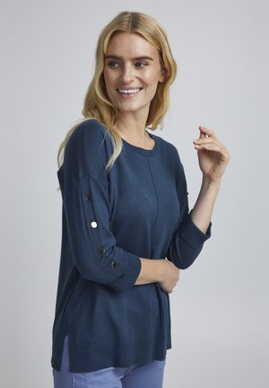 Marineblaues Sweatshirt aus weichem Material, mit Dreiviertelärmeln und Knopfakzenten sowie seitlichen Schlitzen am unteren Ende für eine lässige Passform.