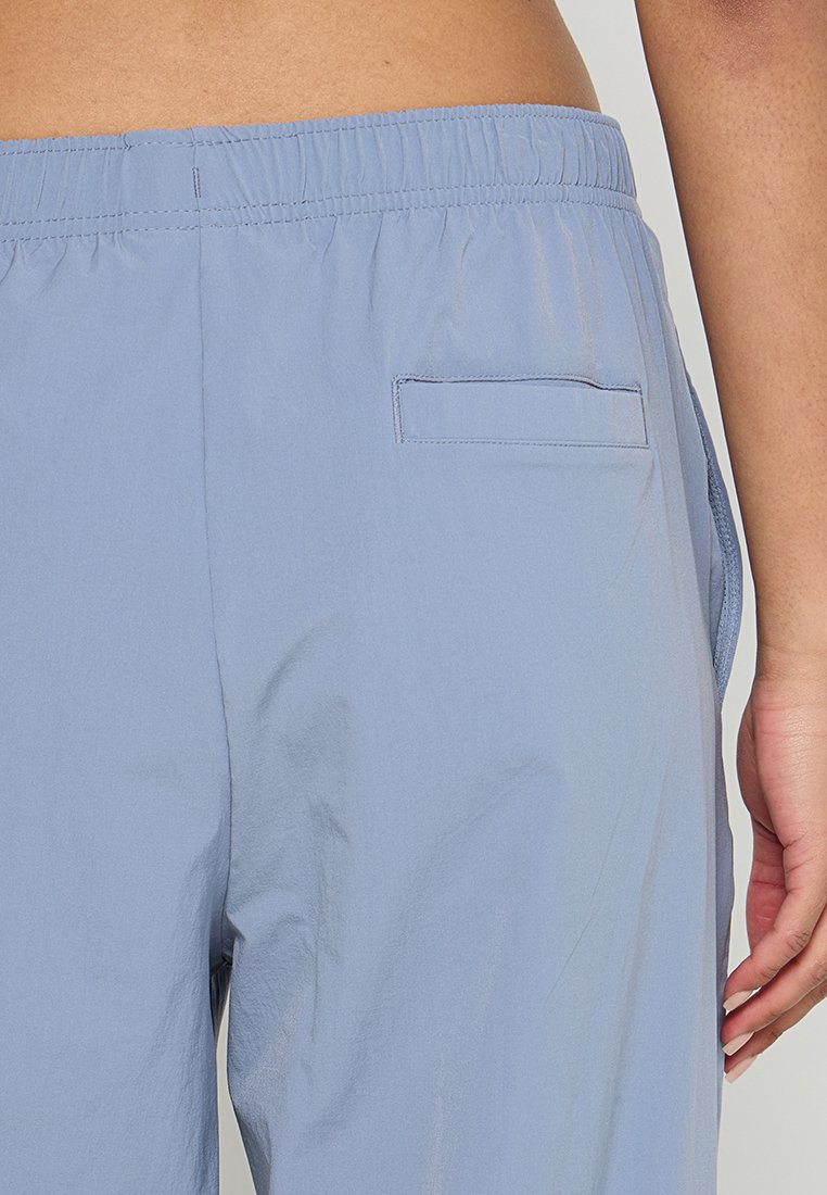 Pantalones ligeros de color azul claro con cintura elástica, que cuentan con un bolsillo trasero y una textura suave. Diseño casual con costuras laterales.