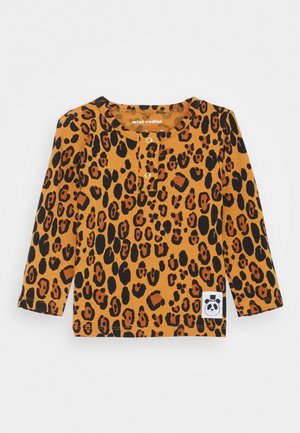 Camisa de manga larga en naranja con estampado de leopardo negro. Presenta un cuello redondo y cierres a presión en la parte frontal. Incluye un parche con el logo de un panda.