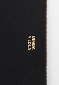 Pochette in tessuto nero con logo dorato "BIMBA Y LOLA". Presenta una texture liscia e una zip, caratterizzata da un design minimalista e linee pulite.