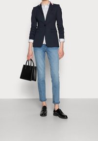 Granatowa marynarka na jeden guzik, pasiasta koszula, jasnoniebieskie dżinsy i czarna torebka. Całość dopełniają lakierowane buty na obcasie.