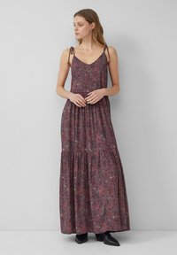 Kwiatowa sukienka maxi w ciemnoczerwonym i purpurowym kolorze, z regulowanymi ramiączkami, dekoltem w serek, marszczoną talią i warstwową spódnicą. Noszona z czarnymi botkami do kostek.