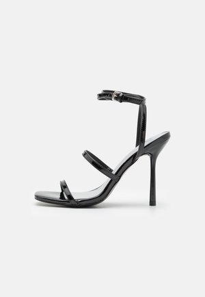 Fekete lakkbőr magassarkú szandál, három vízszintes pánttal és állítható bokapánttal. Sleek sziluett és fényes felület.