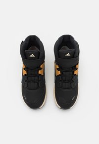 Svarta hög-top sneakers med guld accenter, ovandel av mesh och syntetmaterial, gummisula och snörsystem. Texturerad detaljering på sidorna.