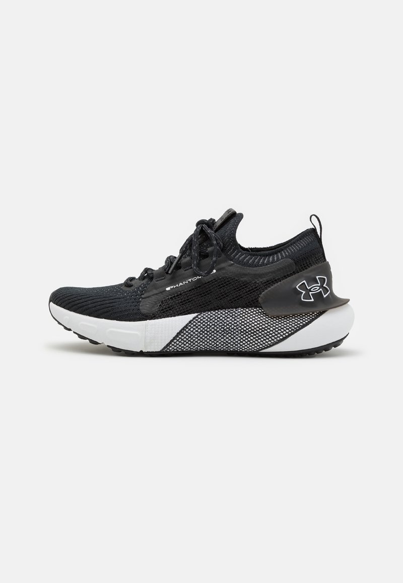 Chaussure de sport noire et blanche à coupe basse avec tige en maille, fermeture à lacets, semelle intermédiaire texturée et logo Under Armour sur le talon.