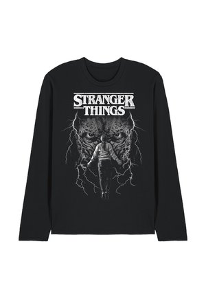 Schwarzes Langarmshirt mit dem Schriftzug "Stranger Things", das eine Person zeigt, die schwebt, umgeben von Blitzen und einem großen Monstergesicht im Hintergrund.