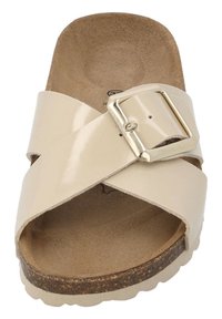 Beige slide sandal with crossed glossy straps and a gold buckle. Cork midsole and textured footbed, featuring an open toe design.