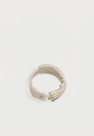 Silver ring designed with two detailed hands reaching toward each other, forming an open-ended band.