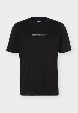 Junger Mann mit dem Rücken zur Kamera, trägt ein schwarzes T-Shirt mit weißem Text „Nichts Schönes ohne Kampf“ auf dem Rücken.
