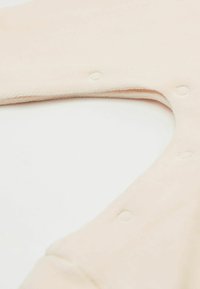 Tissu de pêche doux avec une texture lisse, présentant une découpe circulaire et des fermetures à pression pour la fermeture. Idéal pour un port confortable.