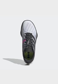 Zapatilla deportiva gris y blanca con acentos negros, que presenta una parte superior de malla texturizada, cordones contrastantes y una plantilla con un patrón.