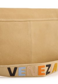Beige Lederhandtasche mit glatter Textur. Akzentuiert mit dem gestickten Wort "VENEZIA" in mehrfarbigen Buchstaben an dem Tragegurt. Schlichtes Design.